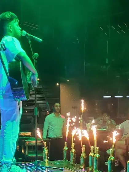An acoustic performance lit by sparklers at a club. This shot captures a magical moment, blending the energy of a celebration with the intimacy of a solo guitar performance.