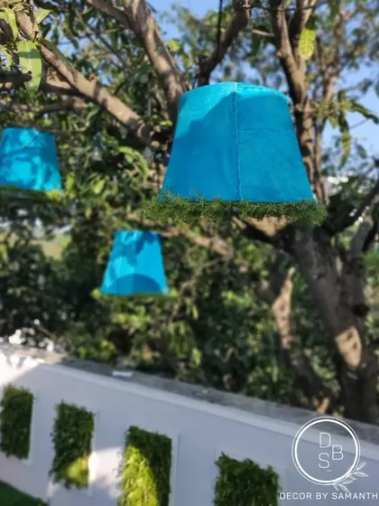 A detail shot of the unique blue lampshades hanging from the trees, which added an unexpected and whimsical pop of color to the decor.