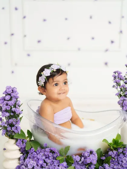 Looking up with a sweet expression from her lavender-filled tub. The soft colors and her gentle smile create a truly lovely portrait.