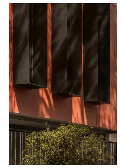 Slender metal fins were introduced to refine daylight control. The tree’s shifting shadows animate the facade throughout the day, turning the building into a dynamic canvas.