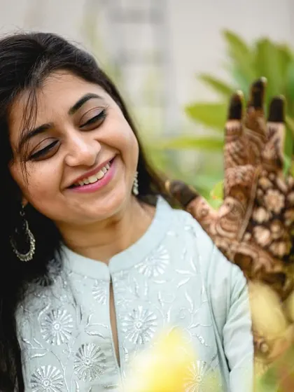 A sweet, candid shot of Poorva admiring her henna design among the flowers in her garden.