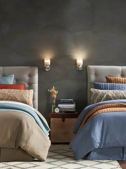 A symmetrical shot of twin beds, showcasing two different colorways of a bedding collection. This is an effective way to display product variety within a single, well-composed image for catalog or commercial use.