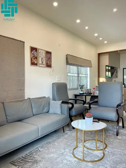 This open-plan living area uses a simple gray and wood color scheme. The comfortable gray sofa is paired with modern armchairs and a nested coffee table with a gold frame for a touch of elegance.