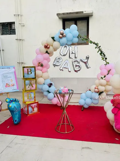 The full setup for a lovely 'Oh Baby' themed baby shower on a terrace. The circular balloon arch and other themed elements come together to create a perfect party space.