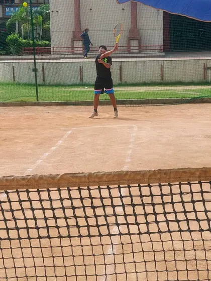 A player preparing to hit a high ball during a competitive match. We train our players to handle shots of all types and heights on the court.