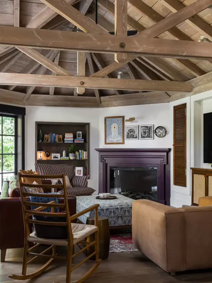 A cozy family room in the Saratoga home, complete with a fireplace and comfortable, deep-seated sofas. We used a mix of patterns and textures, from the striped armchair to the patterned ottoman, to create a layered and lived-in feel. The rocking chair adds a touch of traditional comfort.