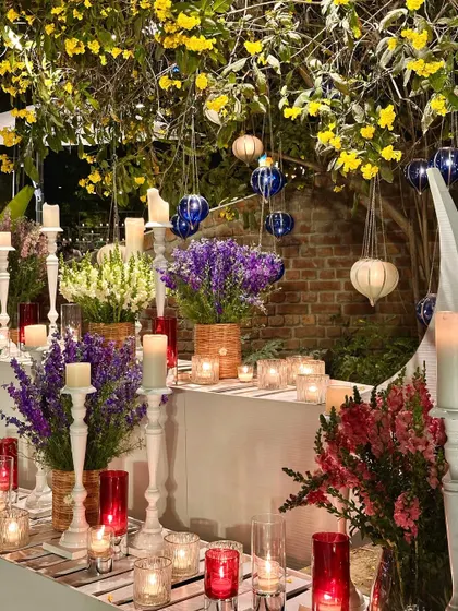 A beautiful tablescape with purple and red flowers, white candelabras, and hanging glass lanterns.