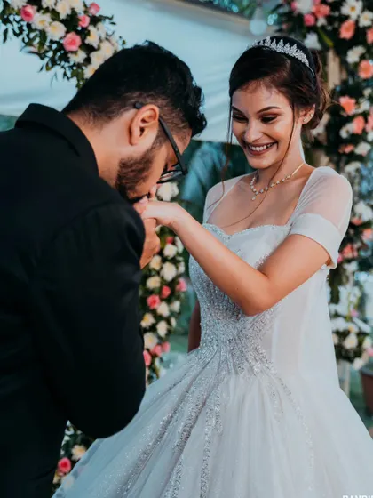 The groom tenderly kissing the bride's hand, a classic romantic gesture captured beautifully after their ceremony.