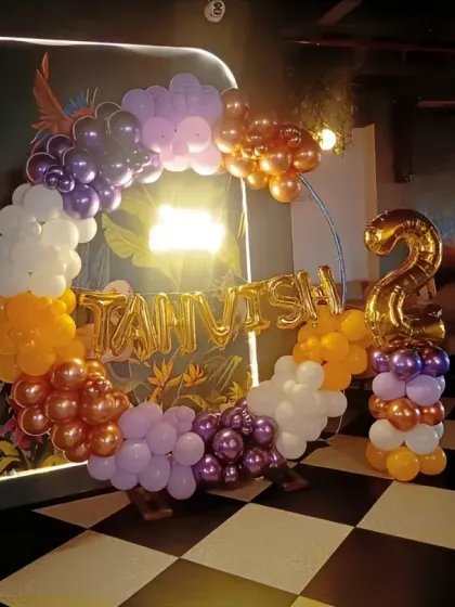 A multi-colored balloon ring in a dimly lit venue for a second birthday party.