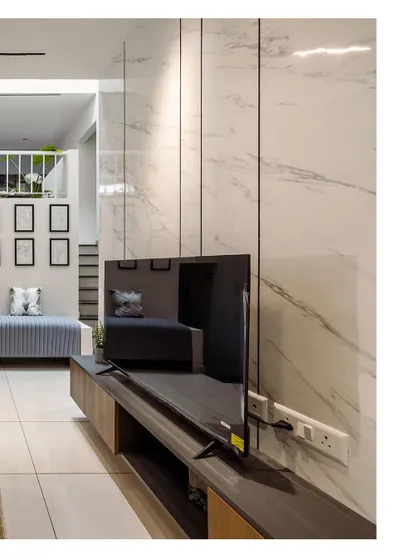 A view of a modern entertainment unit against a white marble-paneled wall. This image showcases the sleek, minimalist design and the effective use of materials in the space.