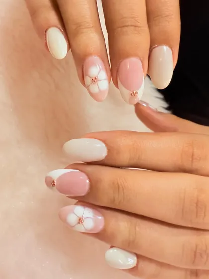 A simple and elegant floral design. This set features a mix of solid white and pink nails with delicate, hand-painted white flowers accented with a tiny rose gold bead.