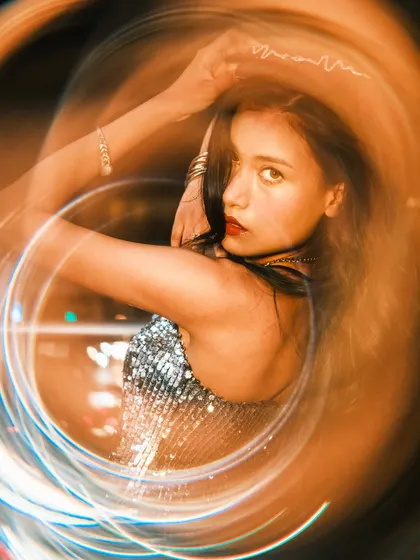 A dynamic pose from the same creative series, where the model looks over her shoulder at the camera. The swirling lights and her pose convey a sense of energy and movement.