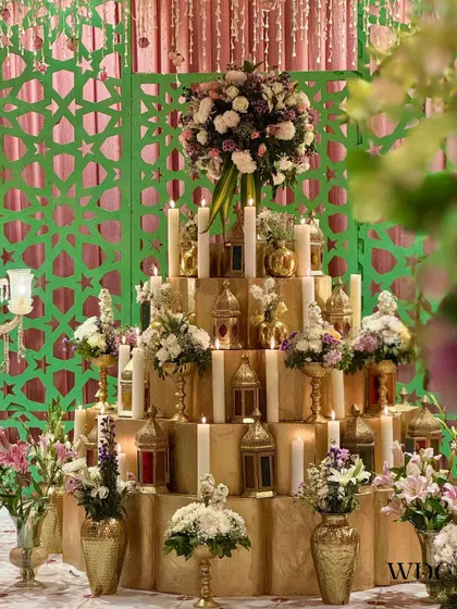 A magnificent candle wall installation. Hundreds of candles and small lanterns were placed on a tiered golden structure, creating a warm and mesmerizing focal point.