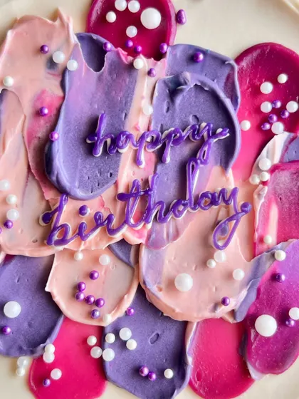 A close-up of my abstract buttercream art. I use a palette knife to create textured strokes in shades of pink, purple, and fuchsia, topped with delicate sugar pearls for a modern, artistic birthday cake.