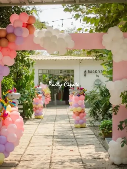 The entrance walkway for the unicorn party, featuring a pink arch with a pastel balloon garland and unicorn-themed pillars guiding the way.