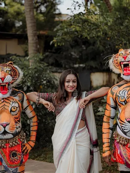 A unique and vibrant photo featuring a woman posing with two Pulikali (tiger dance) performers, a famous folk art from my hometown of Thrissur.
