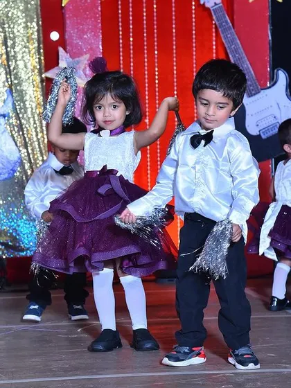 A close-up of the young dancers in their rock-and-roll themed outfits, showing the shiny satin shirts and fun pom-poms.