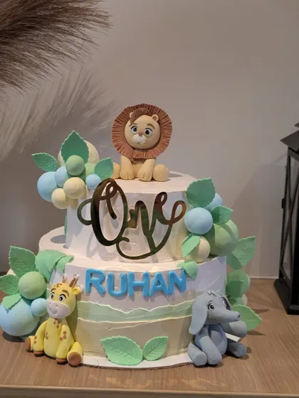 A sweet two-tier "Wild One" cake for a first birthday party. I handcrafted the adorable fondant lion, giraffe, and elephant figures to create a gentle and charming jungle animal theme.