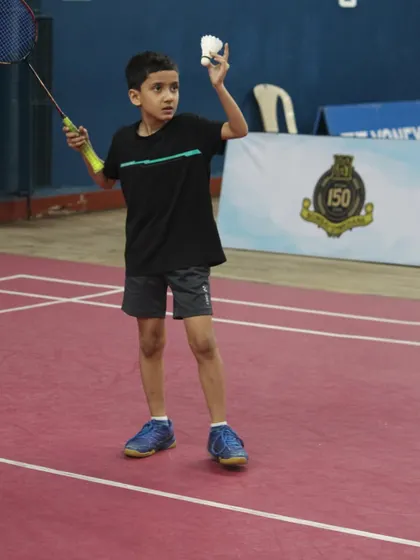 The focus and determination of a young athlete preparing to serve during a competitive match. We create a professional tournament environment where junior players can test their skills and grow.