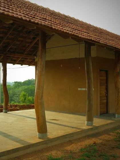 A farm pavilion built near the Savanadurga monolith, using natural and recycled materials. The open-sided structure is supported by rustic, unfinished timber posts.