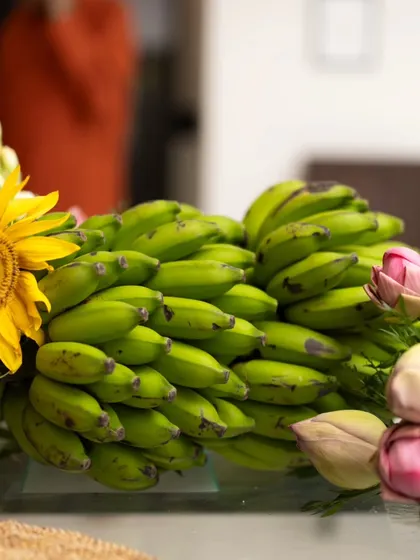 A close-up of the unique centerpiece, highlighting the beautiful contrast between the fresh sunflowers, lotus buds, and a bunch of green bananas.
