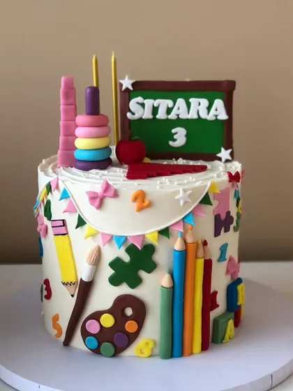 A cake for a little artist, decorated with a chalkboard, paint palette, crayons, and other school-themed elements.