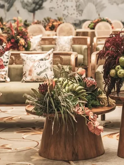 A seating area at the 'Orchard of Life' naming ceremony, with beautiful floral arrangements on wooden tables.
