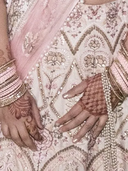 A detailed view of the fine threadwork on the lehenga skirt. The combination of pink and gold threads creates a subtle yet rich texture.