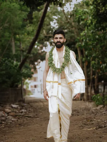 A striking portrait of the groom walking along a path in his traditional wedding attire.