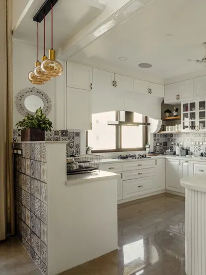 A view of the all-white kitchen from image 148, showing the Moroccan-inspired tile backsplash and island partition.