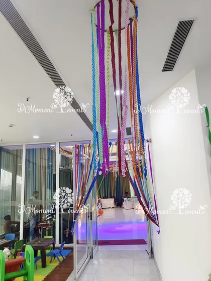 A hanging canopy made of colorful ribbons adds a whimsical and artistic touch to the party's entryway.