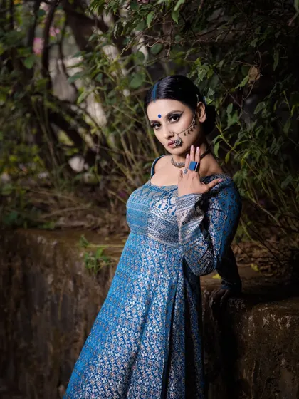 A fashion shoot for a designer brand, focusing on creating a look of royal elegance. The model's pose, the rich blue brocade outfit, and the dramatic makeup come together to create a powerful and artistic image.