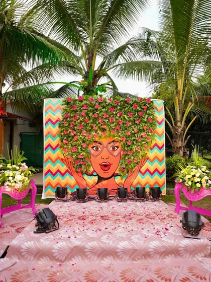 A quirky and artistic backdrop for a fun-filled Mehendi. This hand-painted mural with a 3D floral hairstyle is a great example of how we bring unique, personalized ideas to life for a truly memorable event.