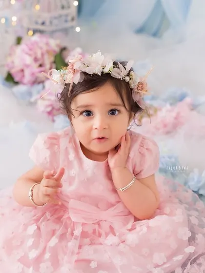 A close-up of the baby girl's expressive face. Her thoughtful look and the beautiful floral crown make for an enchanting portrait.