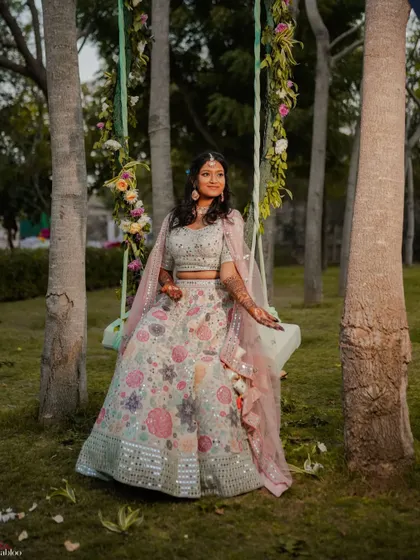 A dreamy portrait of the bride, Priya, on a decorated swing at her Mehendi. The outdoor setting and floral decor create a beautiful, romantic atmosphere.