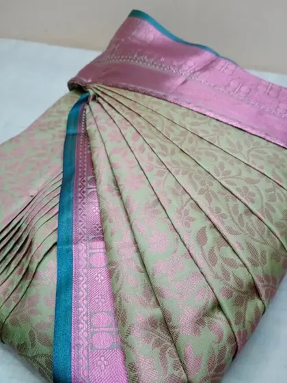 The pleats on this light green and pink saree have been customized based on the client's physique for the most flattering fit.