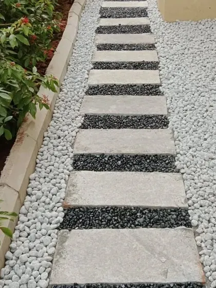 A stylish pathway using stone pavers set in a bed of white and black pebbles. This creates a striking visual contrast and is very low maintenance.