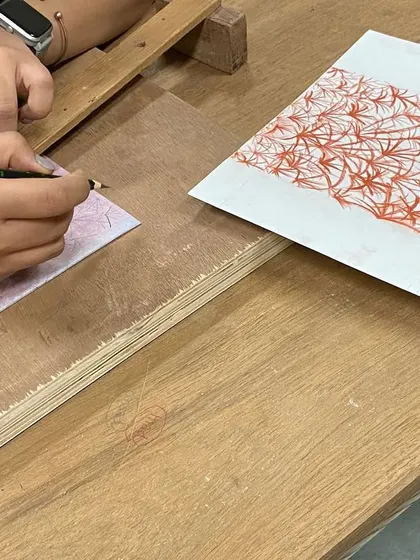 A student carefully tracing a design onto a plate. Teaching workshops like this allows for an exchange of ideas and a shared passion for the craft of making.