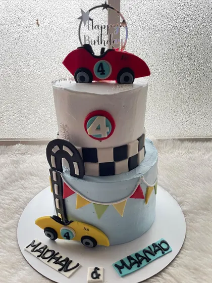 A two-tier race car cake for a 4th birthday. The checkered flag pattern and speedy cars make it a winner for any little racing fan.
