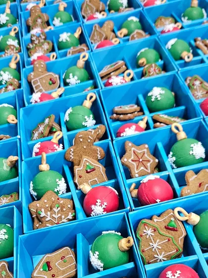 An overhead shot of our Christmas assortment boxes being filled with gingerbread cookies and colorful chocolate bombs. It's a sight of pure holiday cheer!