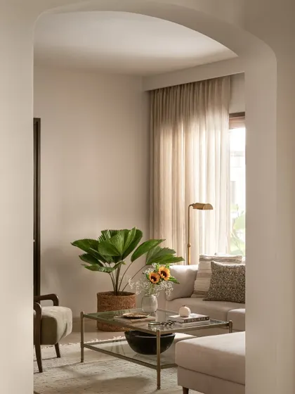A view into the formal living room through one of the home's signature soft arches. The neutral palette and natural light create a calm and modern presence that draws you in.