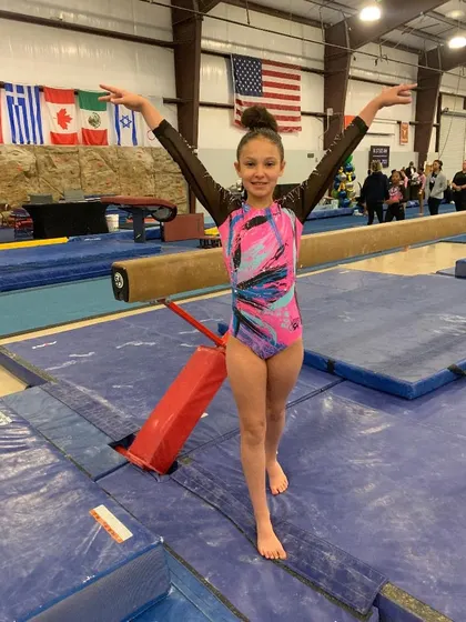 A young Xcel athlete strikes a confident pose on the floor during the State meet.