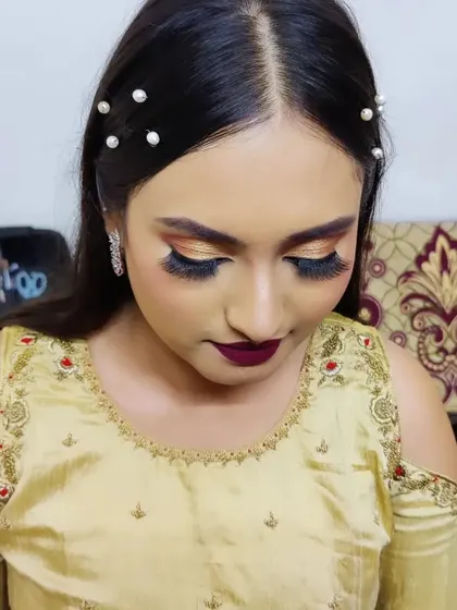 A bold party look with golden glitter eyeshadow and a deep berry lip. The pearl hairpins add a touch of modern elegance.