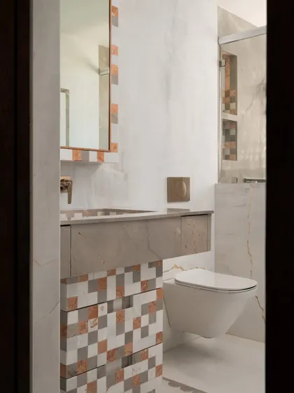 This bathroom in our Gingham Dreams project features a striking mosaic of pixelated marble tiles in shades of grey, white, and terracotta, which flows from the vanity onto the shower wall.