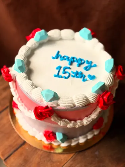 A colorful cake for a 15th birthday, decorated with buttercream gems and roses.