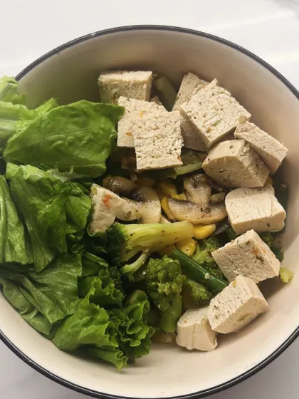 A bowl of sautéed vegetables with tofu, broccoli, and mushrooms, served with fresh lettuce. A perfect meal for a metabolism boost.