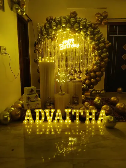 A glamorous birthday decoration with a full arch of chrome gold balloons against a shimmer curtain, creating a luxurious feel.