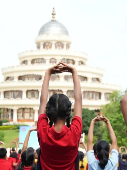 Young students practice a simple stretching asana during an outdoor yoga class. We teach children yoga in a fun and engaging way, helping them develop body awareness and discipline.