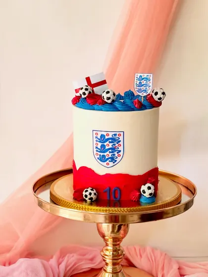 A patriotic football cake for the England team. This design includes the team crest, the flag of England, and is set on a gold cake stand.