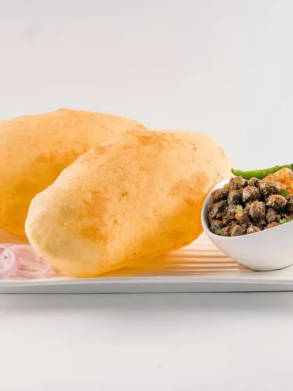 Fluffy, golden-brown Chole Bhature served on a white plate. This clean, catalog-style shot focuses on the texture of the bhature and the accompanying chickpea curry, perfect for a menu display.